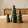 Bosco Quattro in Verde Scuro, set di quattro alberi decorativi, su un tavolo in legno chiaro