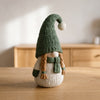 Nisse in Verde Bosco, gnomo nordico a maglia con trecce, su un tavolo in legno chiaro