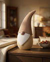 Tomte su una credenza: corpo sabbia rigato, barba bianca, cappello caffelatte curvo